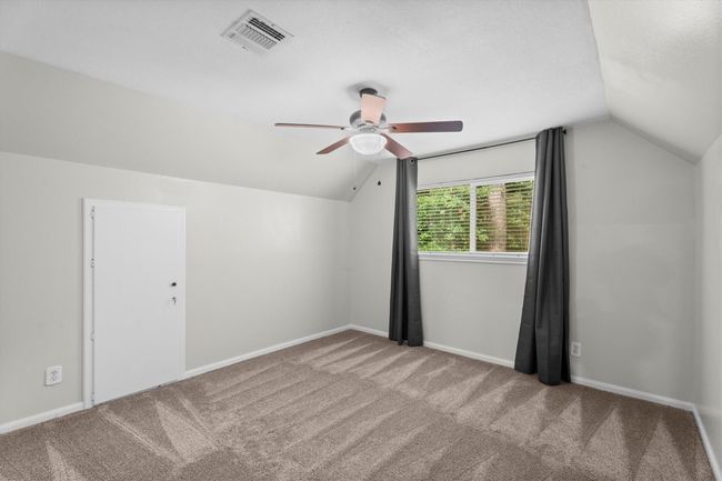 This secondary bedroom also has a bright, neutral-toned look with a sloped ceiling, carpeted floor and a ceiling fan. | Image 29