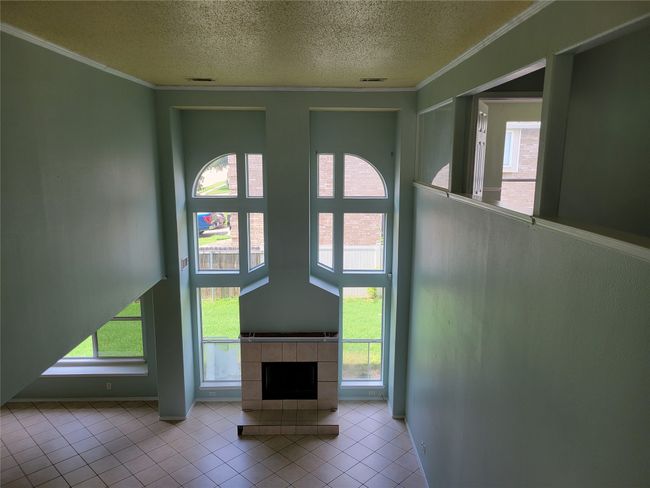 Unfurnished living room featuring a textured ceiling, tile patterned floors, healthy amount of natural light, and ornamental molding | Image 8