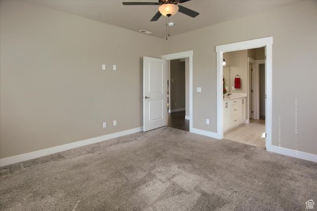Unfurnished bedroom featuring visible vents, baseboards, a ceiling fan, ensuite bath, and light carpet | Image 15