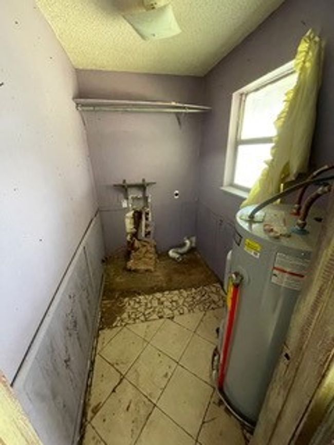 Washroom with a textured ceiling, tile patterned flooring, and water heater | Image 21