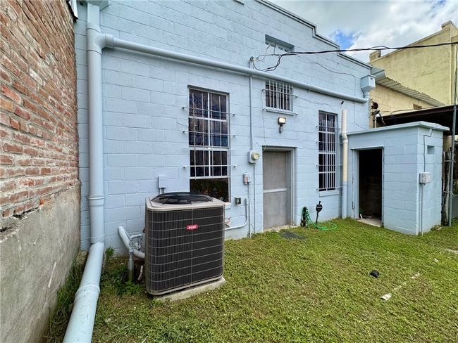 Rear view of Property from alley entrance with central AC, concrete block siding, and a​​‌​​​​‌​​‌‌​‌‌​​​‌‌​​‌‌​‌​​​​​‌ yard | Image 10
