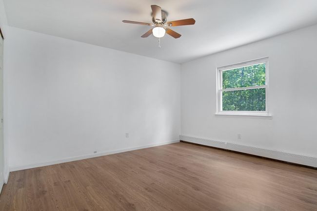Unfurnished room featuring wood finished floors, ceiling fan, baseboards, and a baseboard radiator | Image 22