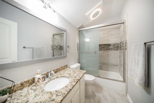 Bathroom featuring vanity, lofted ceiling, enclosed tub / shower combo, and marble look tiles | Image 33