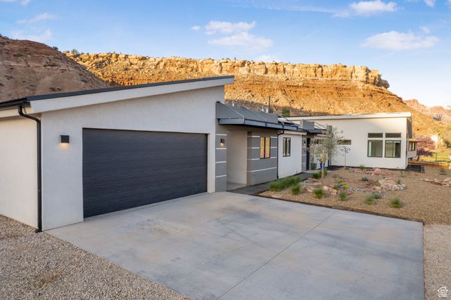 View of front of house with concrete driveway, roof mounted solar panels, a garage, and stucco siding | Image 50