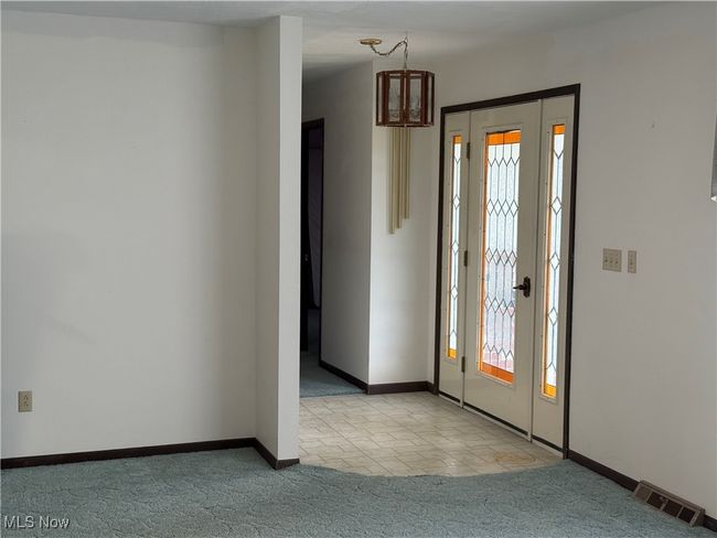 Foyer featuring plenty of natural light, carpet flooring, visible vents, and baseboards | Image 11