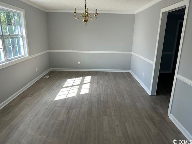 Unfurnished dining area featuring dark wood finished floors, a chandelier, baseboards, and crown molding | Image 12