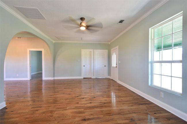 Spare room featuring ornamental molding, arched walkways, a ceiling fan, and wood finished floors | Image 5