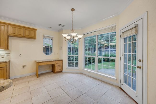 Unfurnished dining area featuring crown molding, plenty of natural light, light tile patterned floors, a chandelier, and an office area | Image 16