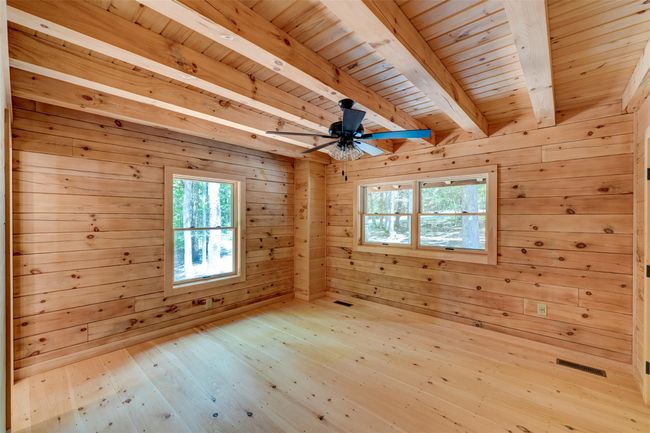 Unfurnished room with plenty of natural light, wood ceiling with exposed beams, wood walls, hardwood / wood-style flooring, and ceiling fan | Image 22