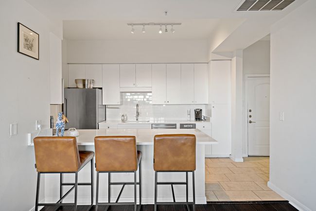 Kitchen with visible vents, a breakfast bar, light countertops, a sink, and stainless steel appliances | Image 10
