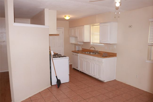 Kitchen with a sink, dishwasher, gas range oven, white cabinets, and a ceiling fan | Image 6