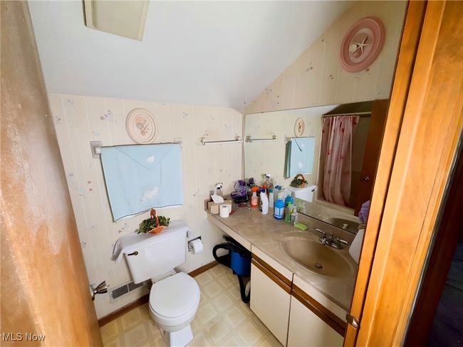 Bathroom with lofted ceiling, tile patterned floors, vanity, and curtained shower | Image 14