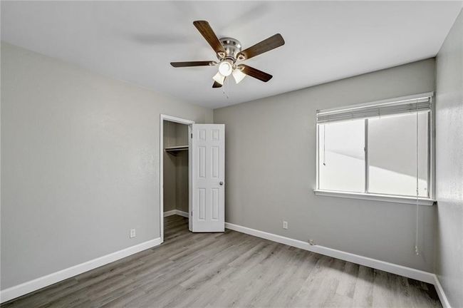 Unfurnished bedroom with wood finished floors, baseboards, a closet, a ceiling fan, and a walk in closet | Image 16