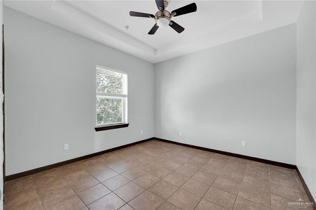 Spare room with a raised ceiling, baseboards, and ceiling fan | Image 5