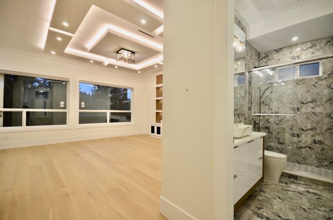 Bathroom featuring a marble finish shower, vanity, wood finished floors, ornamental molding, and recessed lighting | Image 19