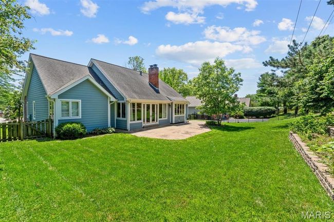 Rear view of house featuring a patio, a chimney, and roof with shingles | Image 63
