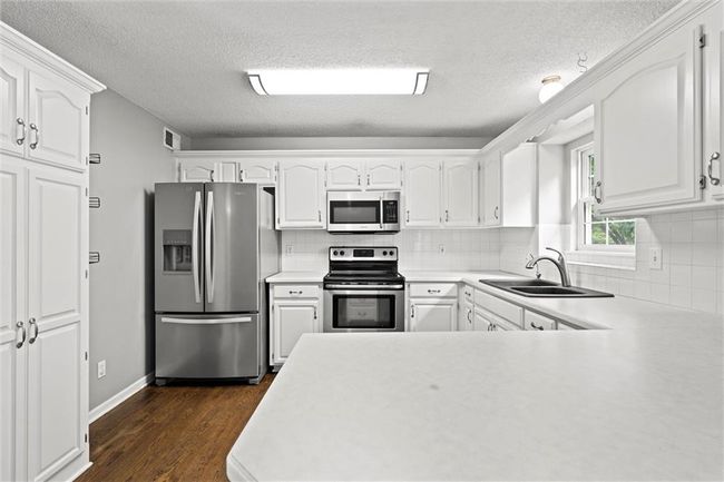 Kitchen with appliances with stainless steel finishes, a textured ceiling, and white cabinetry | Image 10