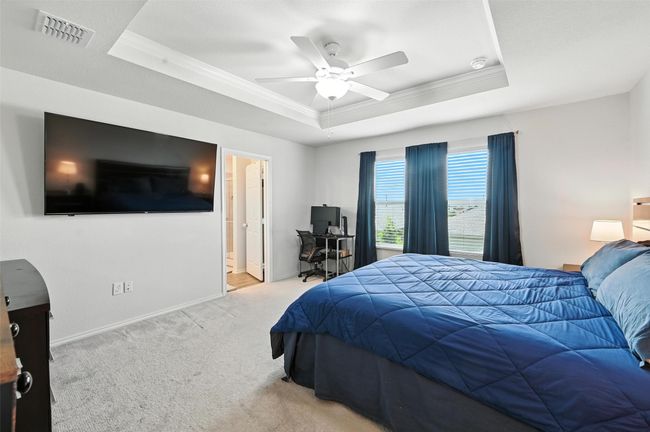 Bedroom with a tray ceiling, ornamental molding, carpet flooring, ceiling fan, and ensuite bath | Image 25