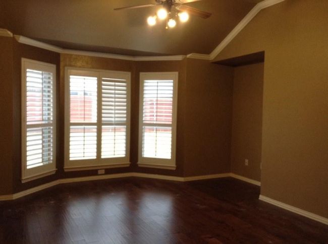 Empty room with dark wood finished floors, ornamental molding, ceiling fan, baseboards, and lofted ceiling | Image 10