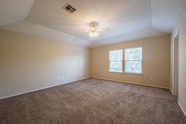 Carpeted spare room featuring a ceiling fan, baseboards, and a raised ceiling | Image 17