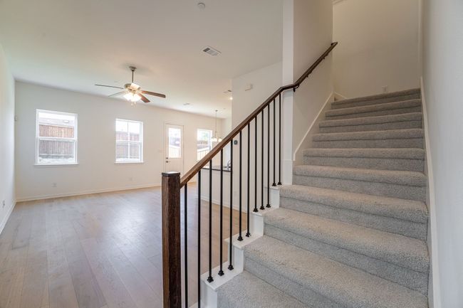 Staircase with wood finished floors, baseboards, a ceiling fan, and visible vents | Image 6