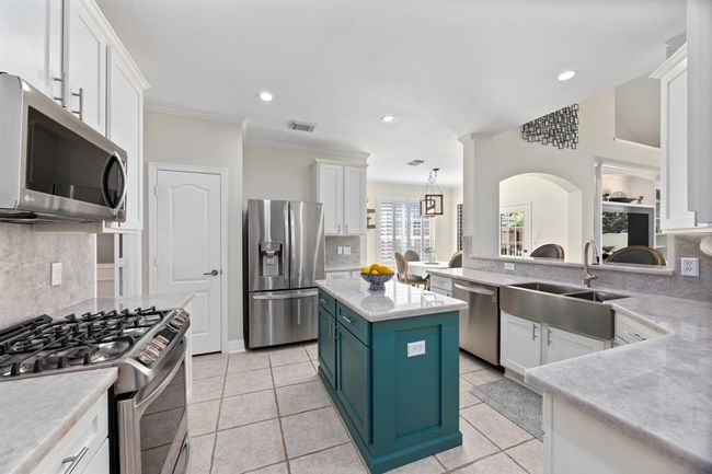 Stunning kitchen includes white cabinetry, illuminato quartzite counters and backsplash, and SS appliances. | Image 15