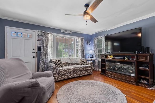 Living room featuring a ceiling fan, wood finished floors, and crown molding | Image 12