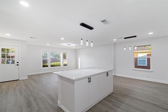 Kitchen featuring a healthy amount of sunlight, white cabinetry, and decorative light fixtures | Image 11