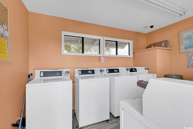 Community laundry room with wood finished floors and separate washer and dryer | Image 32