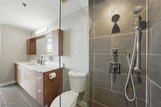 Bathroom with vanity, baseboards, a tile shower, toilet, and tile patterned flooring | Image 24