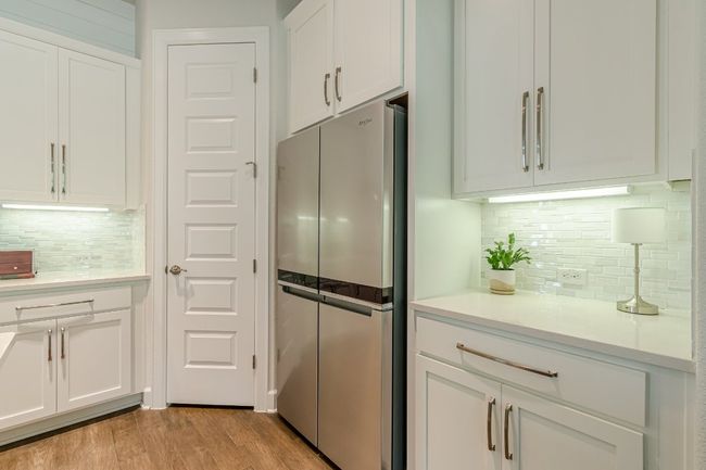 Kitchen with freestanding refrigerator, white cabinetry, backsplash, and light wood-style floors | Image 18