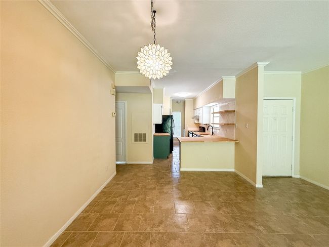 Kitchen with crown molding, freestanding refrigerator, a chandelier, white cabinets, and light countertops | Image 12