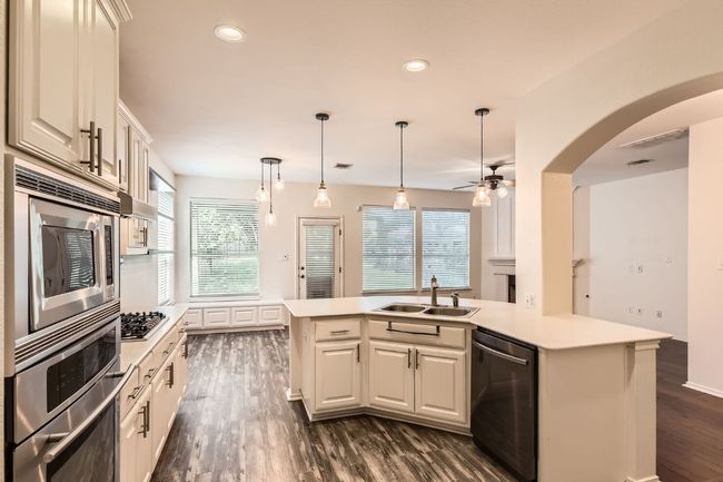 Kitchen with appliances with stainless steel finishes, dark wood-type flooring, light countertops, a ceiling fan, and recessed lighting | Image 13