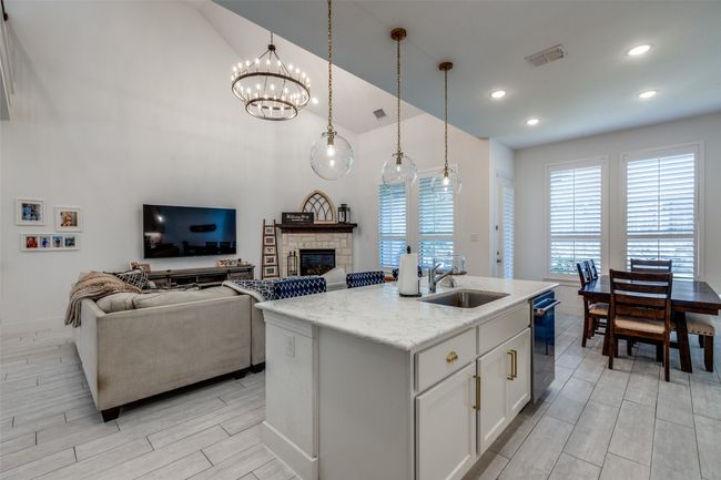 Kitchen featuring a kitchen island with sink, a sink, visible vents, wood tiled floor, and a fireplace | Image 19