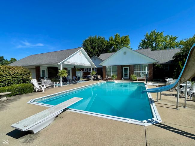 swimming pool featuring a water slide, a diving board, a patio area, an outbuilding, and an exterior structure | Image 10