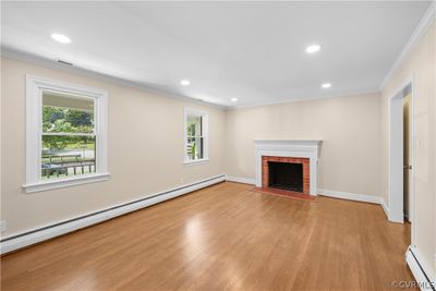 Unfurnished living room with ornamental molding, a baseboard radiator, light hardwood / wood-style flooring, and a brick fireplace | Image 3