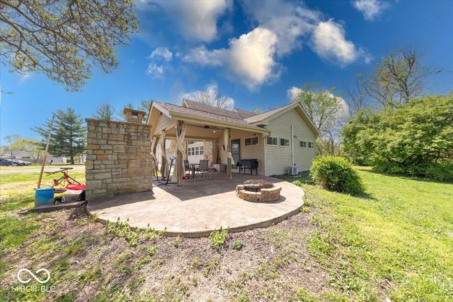 Front of home patio that is covered with electricity, a stone pizza oven, and an outdoor firepit | Image 6
