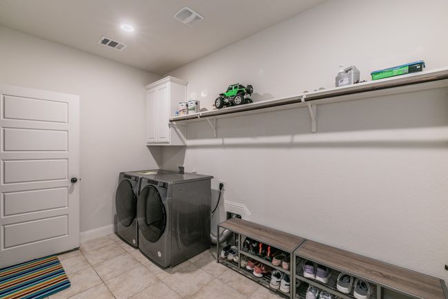 Laundry area featuring visible vents, baseboards, washing machine and dryer, light tile patterned floors, and cabinet space | Image 14