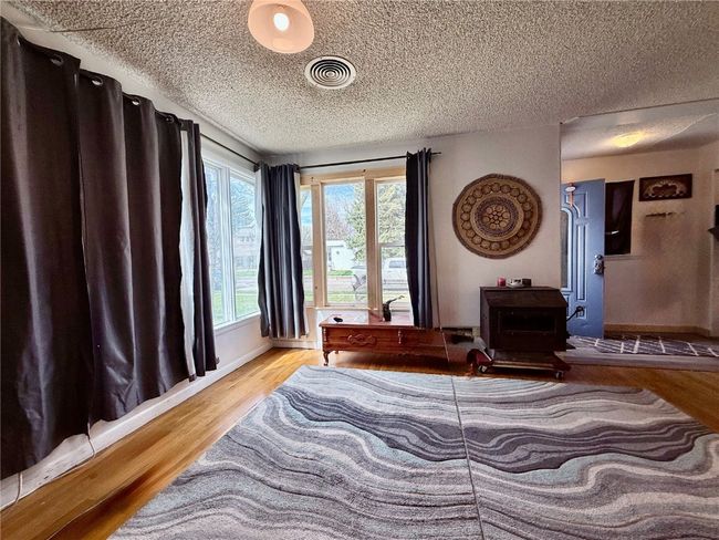 Bedroom featuring wood finished floors, a textured ceiling, baseboards, and a wood stove | Image 8