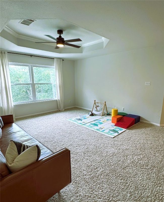 Upstairs living area with a ceiling fan, crown molding, and a raised ceiling. | Image 25