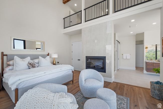 Bedroom featuring a towering ceiling, wood finished floors, a fireplace, and recessed lighting. You can see the railing above where the loft is | Image 40