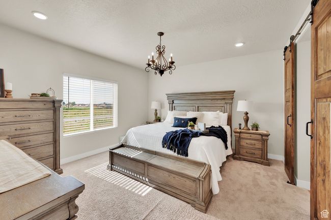 Bedroom featuring a barn door, light colored carpet, baseboards, a chandelier, and recessed lighting | Image 21