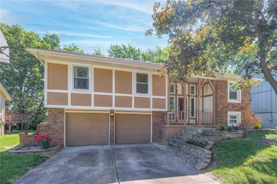 View of front facade with a garage, shade tree and roses | Image 2