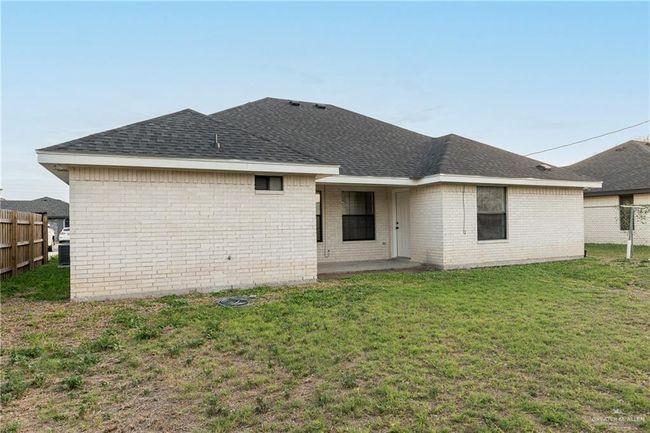 Back of house featuring fence, a lawn, and roof with shingles | Image 12