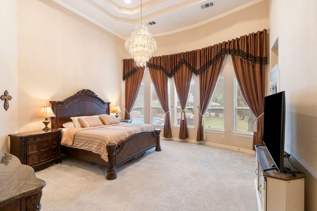 Bedroom featuring a chandelier, ornamental molding, carpet, a raised ceiling, and baseboards | Image 20