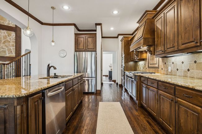 Kitchen with appliances with stainless steel finishes, arched walkways, premium range hood, light stone counters, and ornamental molding | Image 12