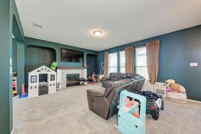 Carpeted living area featuring a fireplace with flush hearth and baseboards | Image 11