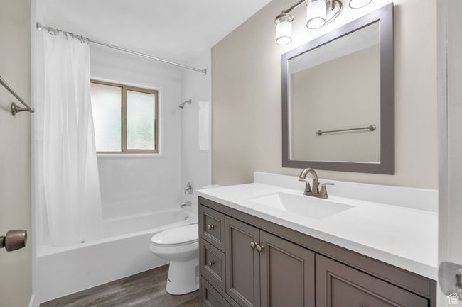 Bathroom featuring shower / tub combo with curtain, vanity, toilet, and wood finished floors | Image 19