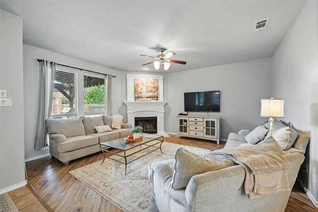 Living room with a ceiling fan, a fireplace with raised hearth, and wood finished floors | Image 14
