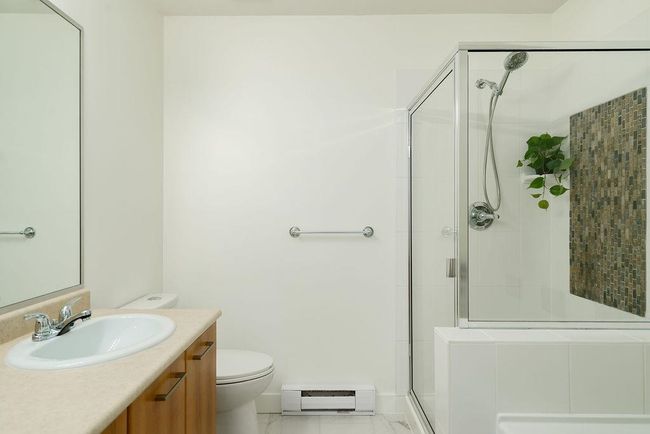 Full bath featuring vanity, a baseboard heating unit, toilet, a shower stall, and marble finish floor | Image 28